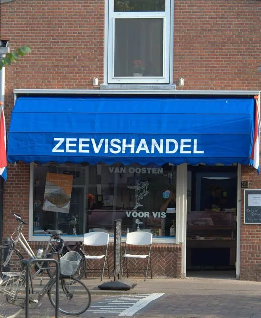 De winkel aan de Buitenwatersloot: de blauwe luifel met ZEEVISHANDEL, twee Nederlandse vlaggen en het bovenraam