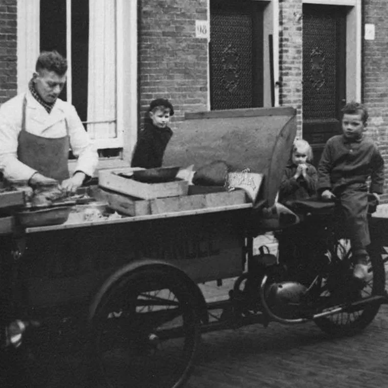 De bakfiets met viskisten voor een woonhuis