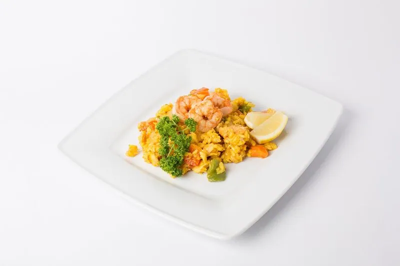 Paella met grote garnalen op een wit bord