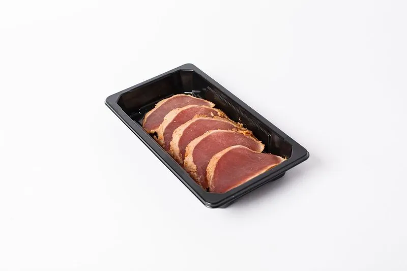 Plakjes gegrilde tonijnsashimi in een zwart bakje
